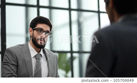 the manager receives a partner in his office sitting at the table the manager receives a partner in his office sitting at the table 105709849