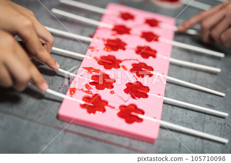 process of making delicious lollipops by pouring them into molds 105710098