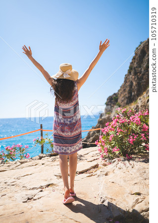 a girl in a summer dress on a stone cliff overlooking the ocean a girl in a summer dress on a stone cliff overlooking the ocean 105710319