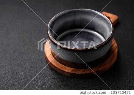 Empty round ceramic bowl on a wooden cutting board in brown color Empty round ceramic bowl on a wooden cutting board in brown color 105710451