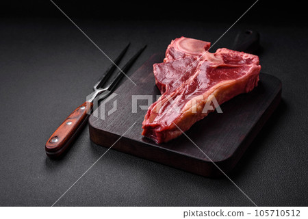 Raw fresh juicy beef t-bone steak with salt, spices and herbs 105710512