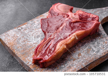 Raw fresh juicy beef t-bone steak with salt, spices and herbs 105710531