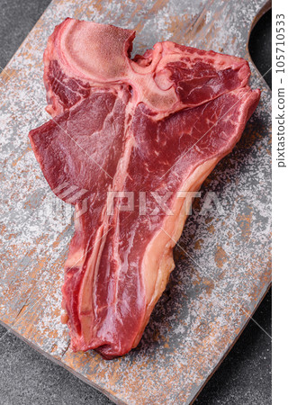 Raw fresh juicy beef t-bone steak with salt, spices and herbs 105710533