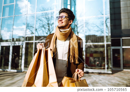 Stylish man with paper packages after shopping. Sale, consumerist, lifestyle concept. Stylish man with paper packages after shopping. Sale, consumerist, lifestyle concept. 105710565