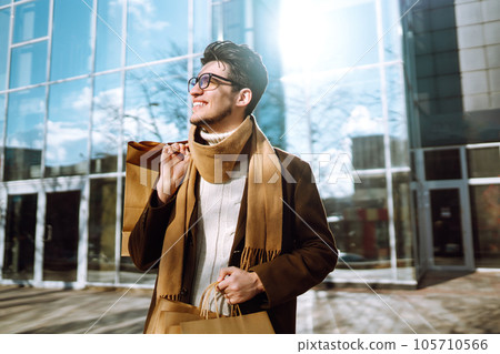 Stylish man with paper packages after shopping. Sale, consumerist, lifestyle concept. Stylish man with paper packages after shopping. Sale, consumerist, lifestyle concept. 105710566