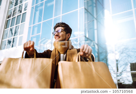 Stylish man with paper packages after shopping. Sale, consumerist, lifestyle concept. 105710568