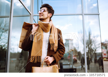 Stylish man with paper packages after shopping. Sale, consumerist, lifestyle concept. Stylish man with paper packages after shopping. Sale, consumerist, lifestyle concept. 105710571