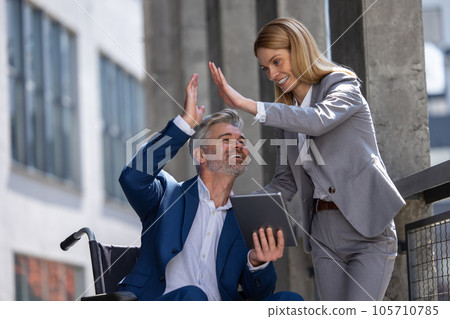 Two business persons giving high five, celebratingfinishing project, man in wheelchair. Two business persons giving high five, celebratingfinishing project, man in wheelchair. 105710785