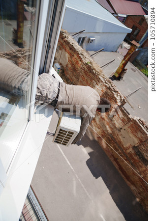 without a face. A man installs an external air conditioner. dangerous work. without a face. A man installs an external air conditioner. dangerous work. 105710894