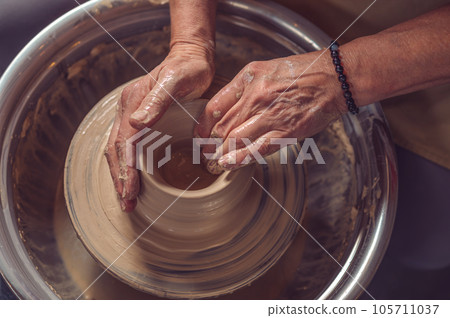 Woman working on pottery wheel and sculpting clay pot. Woman working on pottery wheel and sculpting clay pot. 105711037