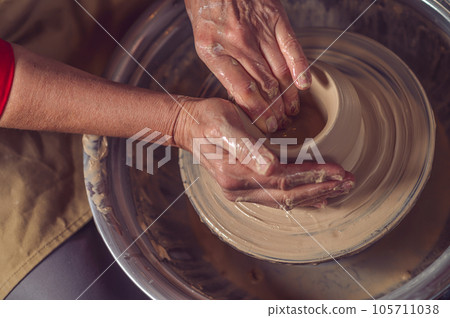 Ceramic bowl on a potter's wheel, ceramist's hands. 105711038
