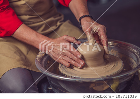 Woman working on pottery wheel and sculpting clay pot. Woman working on pottery wheel and sculpting clay pot. 105711039