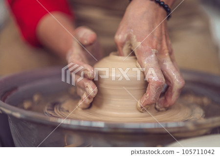 Woman working on pottery wheel and sculpting clay pot. Woman working on pottery wheel and sculpting clay pot. 105711042