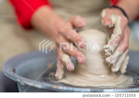 Woman working on potter's wheel in a pottery workshop, creating clay pot. Woman working on potter's wheel in a pottery workshop, creating clay pot. 105711058