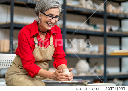Woman working on potters wheel creating clay products at her workshop. Woman working on potters wheel creating clay products at her workshop. 105711065