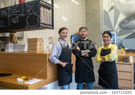 Team of young cafe workers standing together and looking contented 105711095