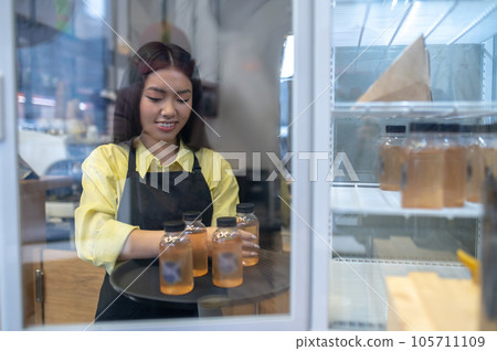 Young girl in apron taking drinks from the fridge Young girl in apron taking drinks from the fridge 105711109