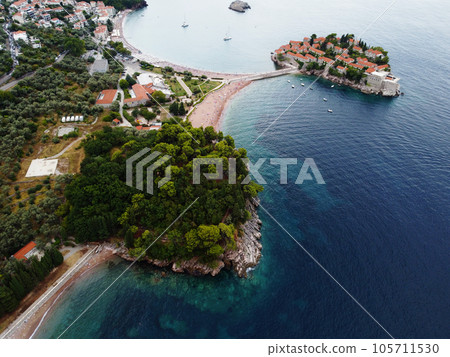 Aerial view of Sveti Stefan island and shore in a beautiful summer day, Montenegro from flying drone. Panoramic above view of Saint Stephen luxury resort. Tourism and leisure concept. Aero photography Aerial view of Sveti Stefan island and shore in a beautiful summer day, Montenegro from flying drone. Panoramic above view of Saint Stephen luxury resort. Tourism and leisure concept. Aero photography 105711530