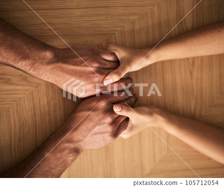 Man and woman holding hands on a table and supporting, helping and comfort each other in marriage couple counseling session from above view. Loving husband and wife touching each other showing care 105712054