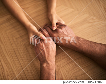 Couple holding hands showing love, romance and support while sitting at a table from above. Top view of a loving husband and wife sharing affectionate touch, caring and helping with a hand gesture Couple holding hands showing love, romance and support while sitting at a table from above. Top view of a loving husband and wife sharing affectionate touch, caring and helping with a hand gesture 105712066