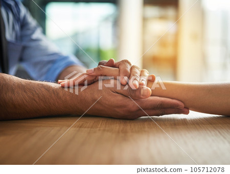 Hands holding together with love, support and care in a touching and bonding moment. Closeup of a close, loving hand hold between two people together. Comforting gesture of sympathy and community Hands holding together with love, support and care in a touching and bonding moment. Closeup of a close, loving hand hold between two people together. Comforting gesture of sympathy and community 105712078