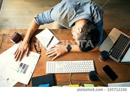 He pushed himself way past his limit. Shot of an exhausted young businessman sleeping at his desk during a late night at work. He pushed himself way past his limit. Shot of an exhausted young businessman sleeping at his desk during a late night at work. 105712280