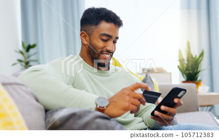 Credit card, finance and man with smartphone for online shopping in lounge at home. Indian, visa and money for e commerce transaction and search the internet for investment or product. 105712383