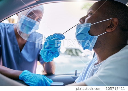 Doctor or nurse doing covid or corona virus test at a drive thru on a man sitting in a car. Medical professional taking nose swab sample from male patient through window with a PCR diagnostic kit. 105712411