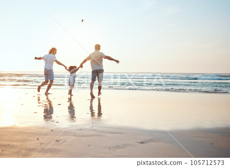 Gay parents holding hands with girl at beach running in water on holiday, vacation and adventure. Lgbtq family, sunset and happy child with fathers by ocean for bonding, relaxing and fun outdoors 105712573
