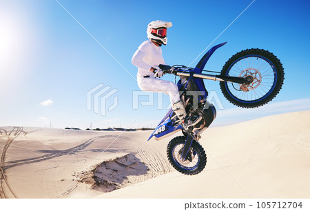 Jump, sports and man on motorcycle on sand for adrenaline, adventure and freedom in desert. Action, extreme motorbike and male person on bike on dunes for training, exercise and race or challenge Jump, sports and man on motorcycle on sand for adrenaline, adventure and freedom in desert. Action, extreme motorbike and male person on bike on dunes for training, exercise and race or challenge 105712704