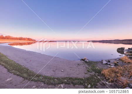 Beautiful, fresh and colorful nature at sunset with calm water near forest. Still, gentle lake against a background of soft, twilight sky with lush green trees, horizon, copy space and relaxing view Beautiful, fresh and colorful nature at sunset with calm water near forest. Still, gentle lake against a background of soft, twilight sky with lush green trees, horizon, copy space and relaxing view 105712865