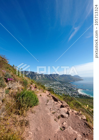 Landscape, mountains and paraglider flying over sea, city in extreme adrenaline sport or adventure hobby. Copy space, blue sky and ocean view of mountain hiking trail with rocks in travel destination 105713324