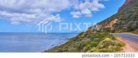Copy space with sea view and a street along the mountain against a cloudy sky background at the coast. Beautiful and scenic coastal landscape of nature to travel or explore on a peaceful road trip Copy space with sea view and a street along the mountain against a cloudy sky background at the coast. Beautiful and scenic coastal landscape of nature to travel or explore on a peaceful road trip 105713333