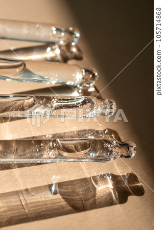 Four pipettes of cosmetic gel on a beige background. Four pipettes of cosmetic gel on a beige background. 105714868