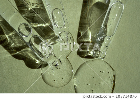 Three pipettes of cosmetic gel on a green background. 105714870