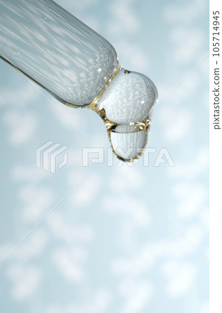 A dripping pipette with a drop of cosmetics gel. 105714945
