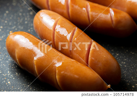 A cooking scene in which the wiener sausage is cut in and baked in a frying pan. 105714978