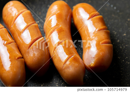 A cooking scene in which the wiener sausage is cut in and baked in a frying pan. A cooking scene in which the wiener sausage is cut in and baked in a frying pan. 105714979