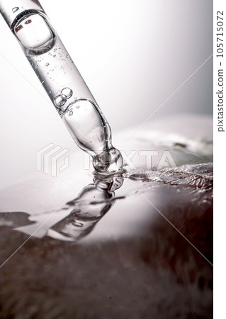 Pipette on a large piece of ice with frozen flowers. Pipette on a large piece of ice with frozen flowers. 105715072