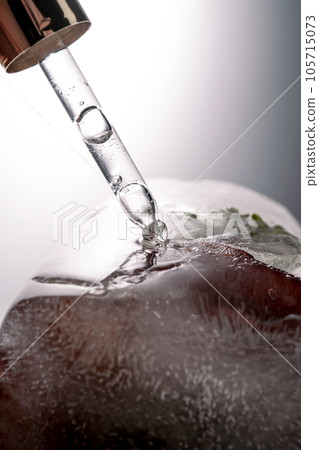 Pipette on a large piece of ice with frozen flowers. Pipette on a large piece of ice with frozen flowers. 105715073