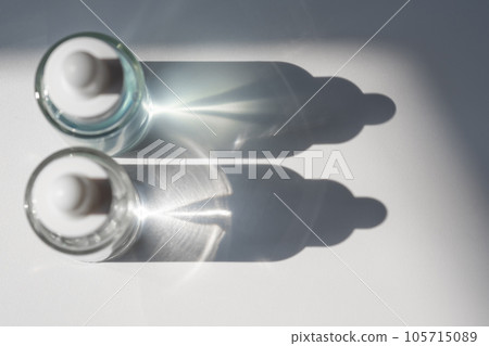 Two laconic bottles of cosmetic liquid in the rays of the harsh sun. Two laconic bottles of cosmetic liquid in the rays of the harsh sun. 105715089