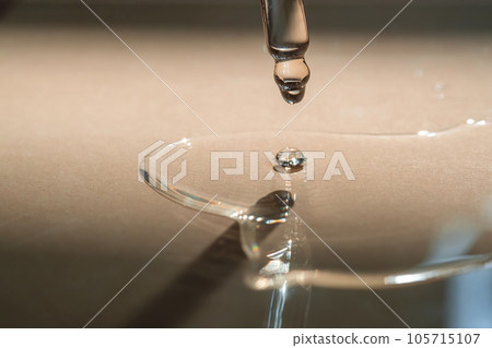 A Dripping Pipette of cosmetic gel on a beige background. A Dripping Pipette of cosmetic gel on a beige background. 105715107