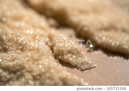 The texture of a yellow shining scrub on a beige background. The texture of a yellow shining scrub on a beige background. 105715108