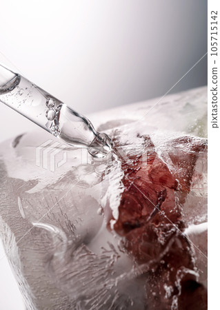 Pipette on a large piece of ice with frozen flowers. Pipette on a large piece of ice with frozen flowers. 105715142