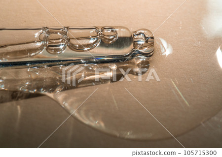 A pipette of cosmetic gel on a beige background. A pipette of cosmetic gel on a beige background. 105715300
