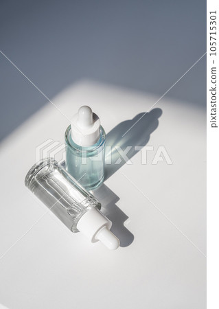 Two laconic bottles of cosmetic liquid in the rays of the harsh sun. 105715301