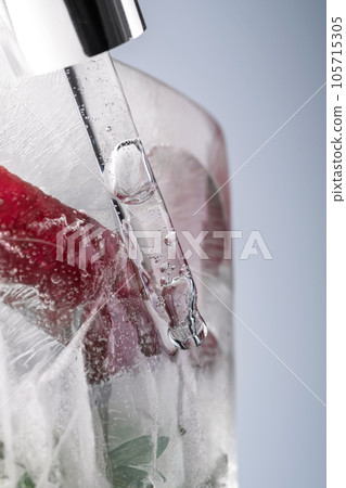 Pipette on a large piece of ice with frozen flowers. 105715305