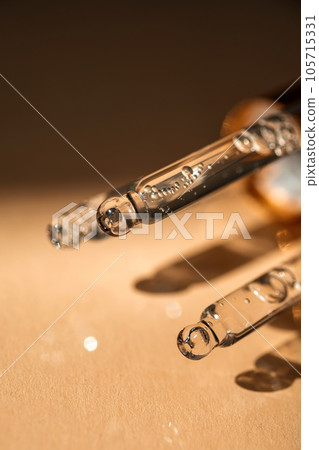 Three pipettes of cosmetic gel on a beige background. 105715331