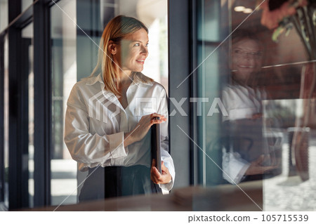 Smiling woman manager standing with laptop in coworking and looking at side. Distance work concept Smiling woman manager standing with laptop in coworking and looking at side. Distance work concept 105715539