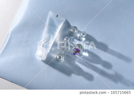 Transparent bottle of cosmetic gel on a blue background with small bottles of water. 105715665